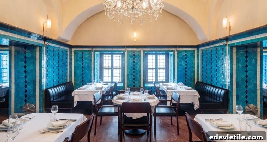 A beautifully designed dining room in Istanbul featuring turquoise tile accents, white tablecloths, and a sparkling chandelier, set for a refined culinary experience.