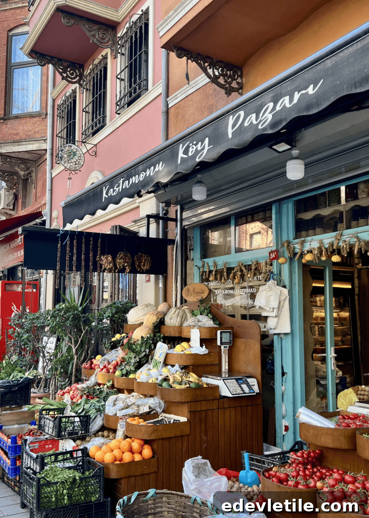 A colorful village-style grocery shop in Istanbul with crates of fresh fruits and vegetables displayed outside under a black awning that reads “Kastamonu Köy Pazarı.”