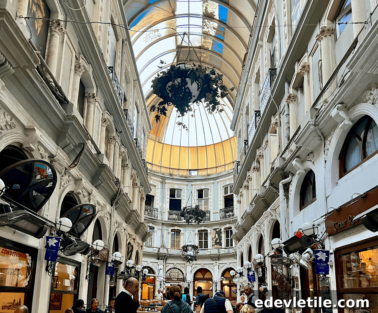 View of the elegant interior of Çiçek Pasajı in Istanbul, a historic arcade filled with cafes and restaurants, under a domed glass roof.