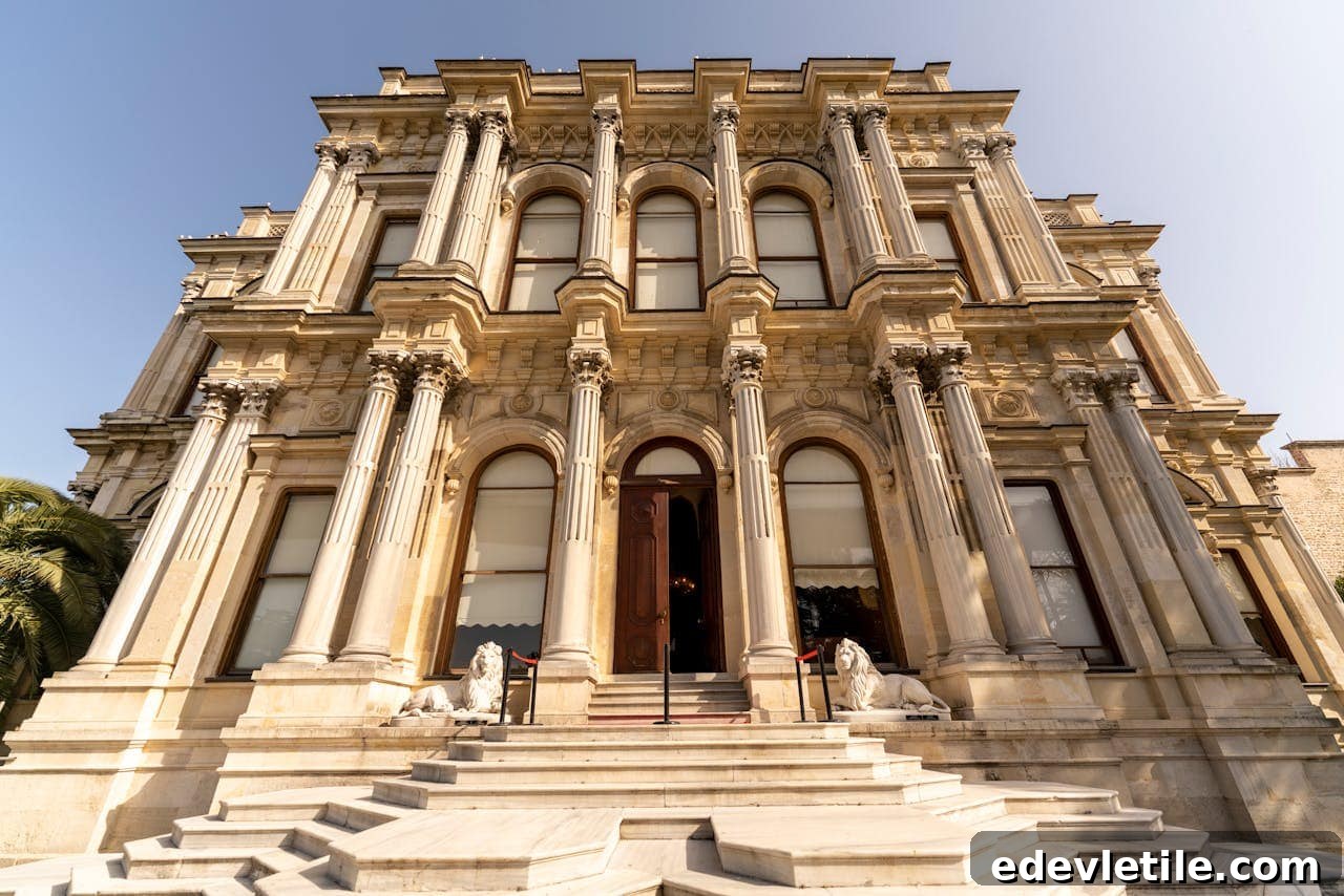 Exterior view of Beylerbeyi Palace’s main entrance, featuring neoclassical architecture with tall arched windows, Corinthian columns, lion statues, and marble steps.