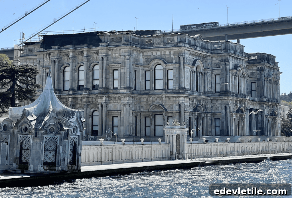 Waterfront view of Beylerbeyi Palace from the Bosphorus, showing its elegant stone façade, arched windows, ornate pavilion, and bridge in the background.