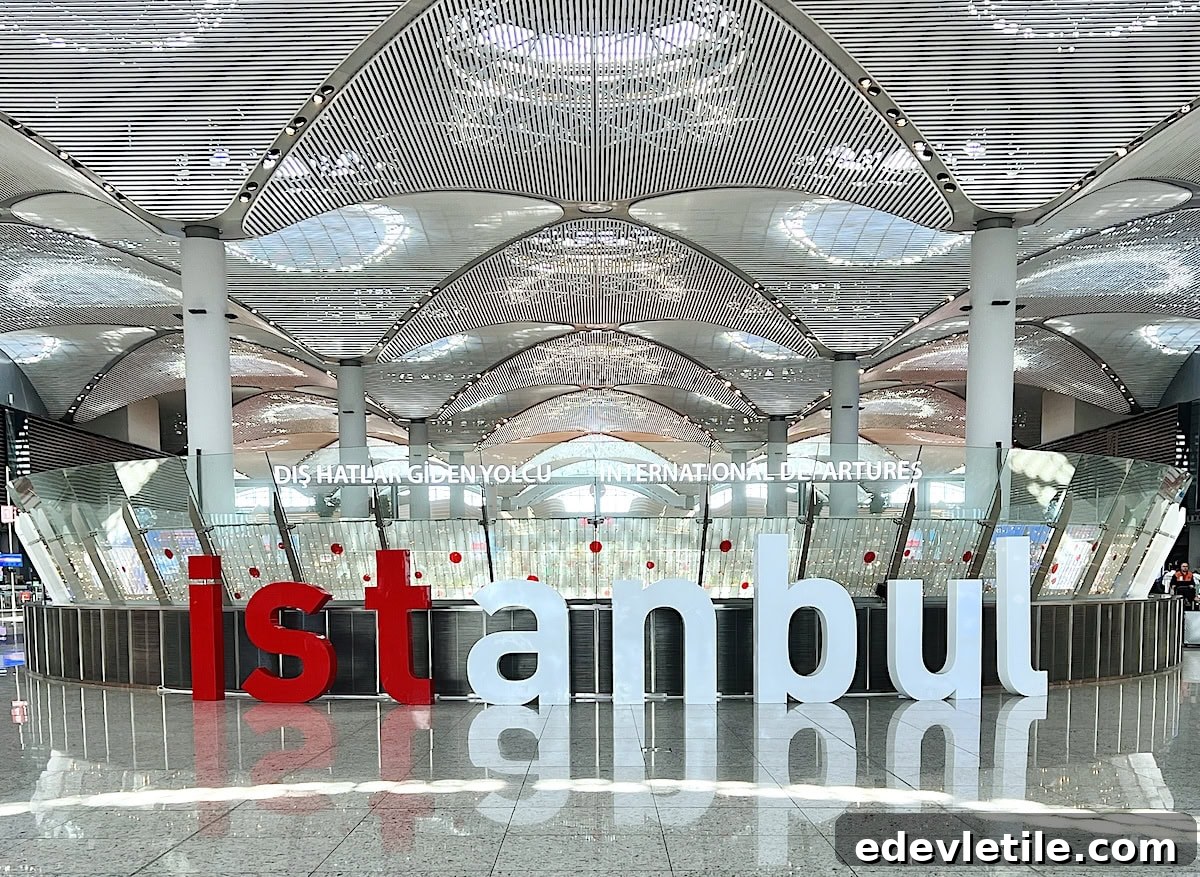 Large open terminal hall inside Istanbul Airport with a curved patterned ceiling and large red and white letters spelling "istanbul" near the international departures area.