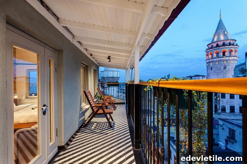 Balcony of a boutique hotel near Galata with wooden chairs and a railing covered in plants overlooking Istanbul rooftops and the illuminated Galata Tower at dusk.