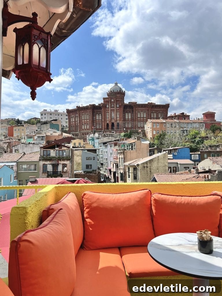 Scenic rooftop view of the red-brick Fener Greek Orthodox College rising above the colorful homes of Balat, seen from a cozy orange terrace lounge.