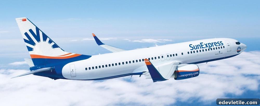 SunExpress plane in mid-air cruising above the clouds, with a bright blue and orange livery and Turkish flag on the tail.