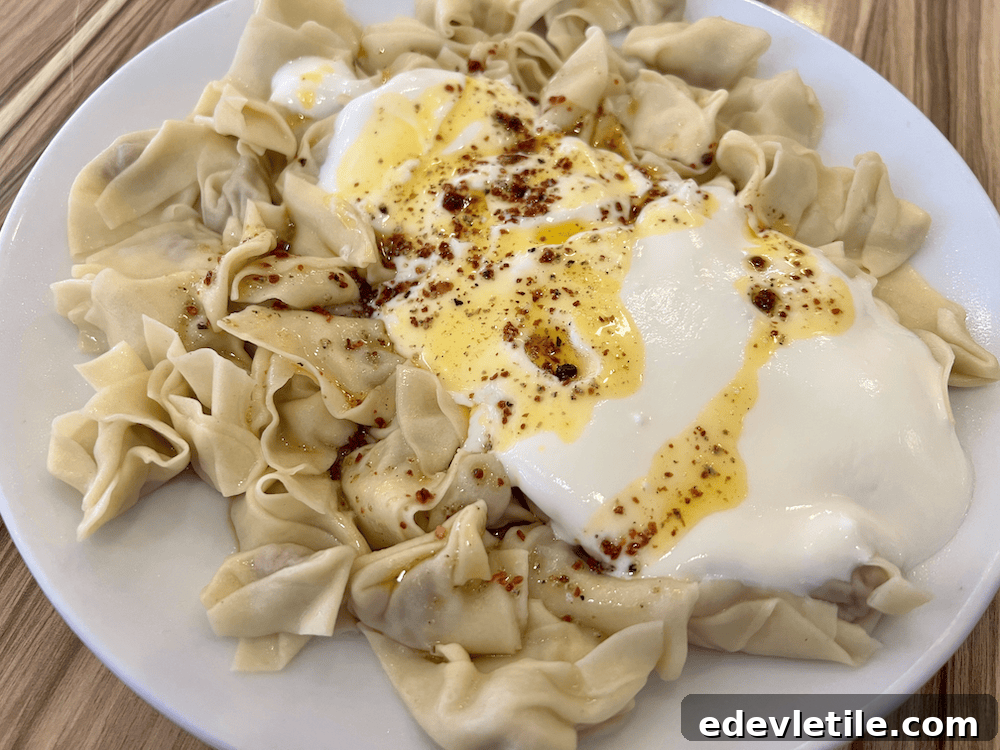 Close-up of a traditional Turkish dish called mantı, served in Sinop with yogurt and spiced butter sauce over hand-folded dumplings on a white plate.