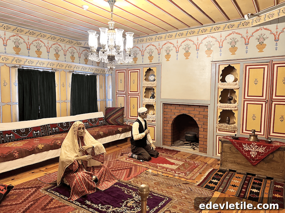 Interior of a traditional Ottoman-style room in the Ethnography Museum of Sinop, with mannequins in period clothing seated on colorful rugs and cushions, surrounded by ornate hand-painted walls and wooden decor.